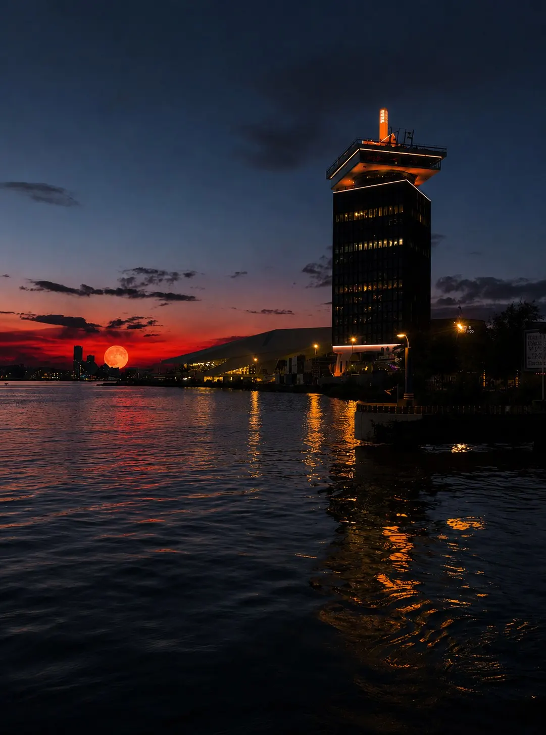 Вежа A'DAM Toren на тлі заходу сонця над водою